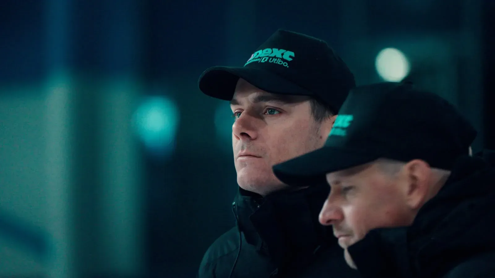 Twee mannen met een Next-pet kijken geconcentreerd toe
